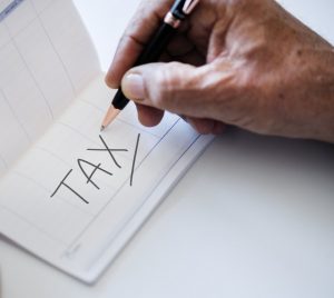 checkbook with a hand writing the word tax
