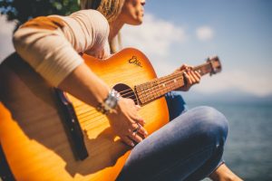 woman playing a guitar by the water