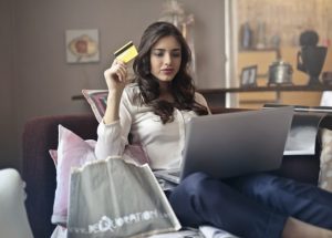 woman using a laptop computer with a gift card in her hand