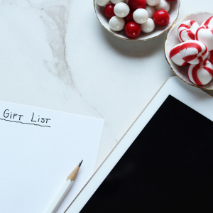 White background with piece of paper saying "Gift List" with peppermint candy and ipad. Avoid Holiday Impulse Shopping