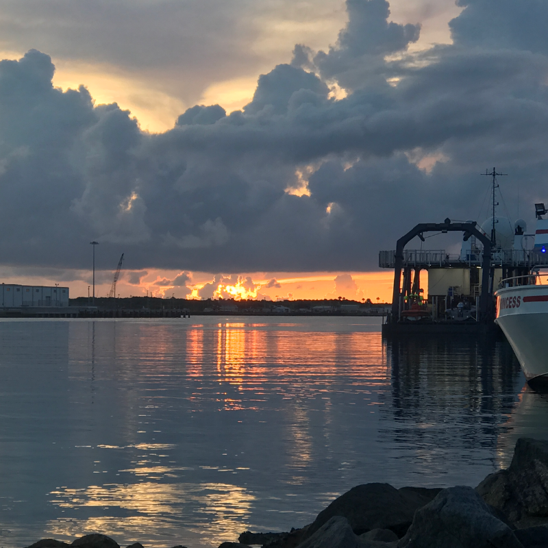 A sunrise behind clouds next to a boat