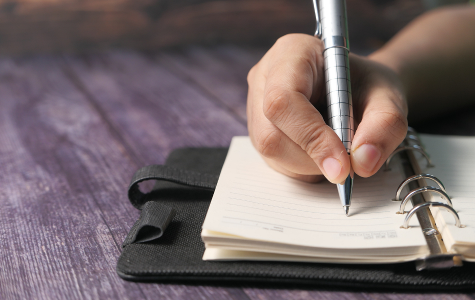 Hand holding pen writing in notebook