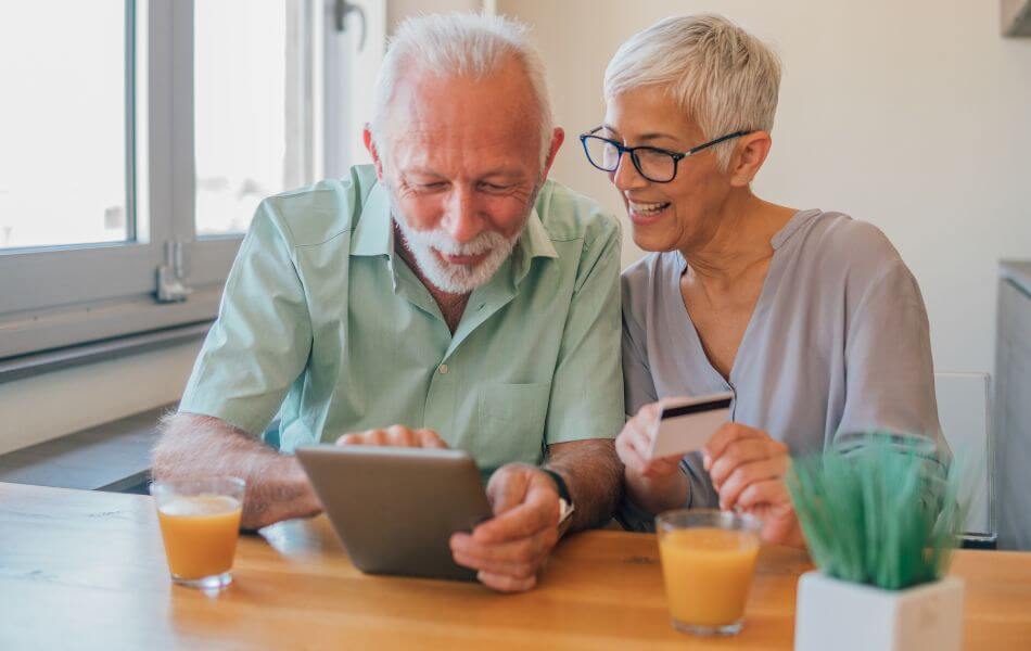 Married couple searching on computer, holding a credit card