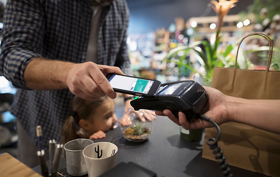Dad using contactless payment on mobile wallet to pay at plant shop