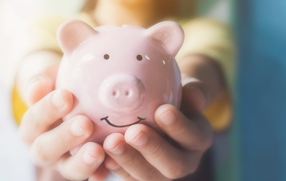 kid hands holding pink piggy bank