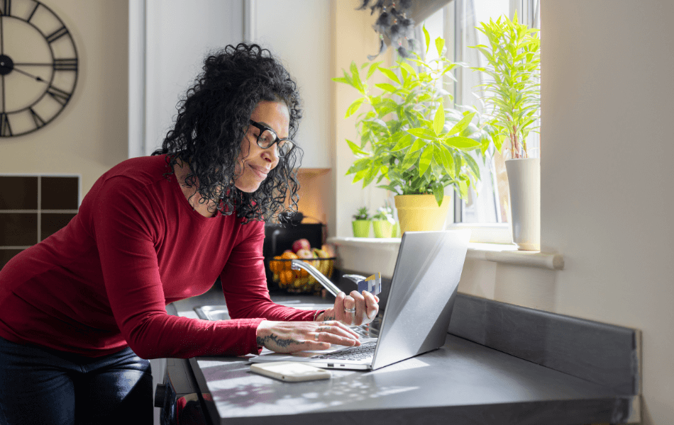 Woman holding credit card and looking at laptop