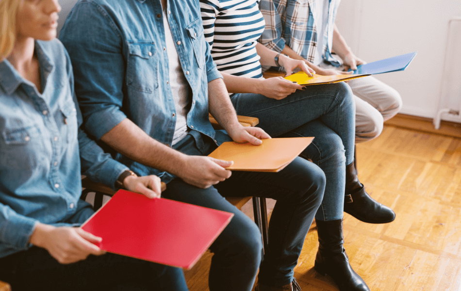 4 people sitting in chairs with folders