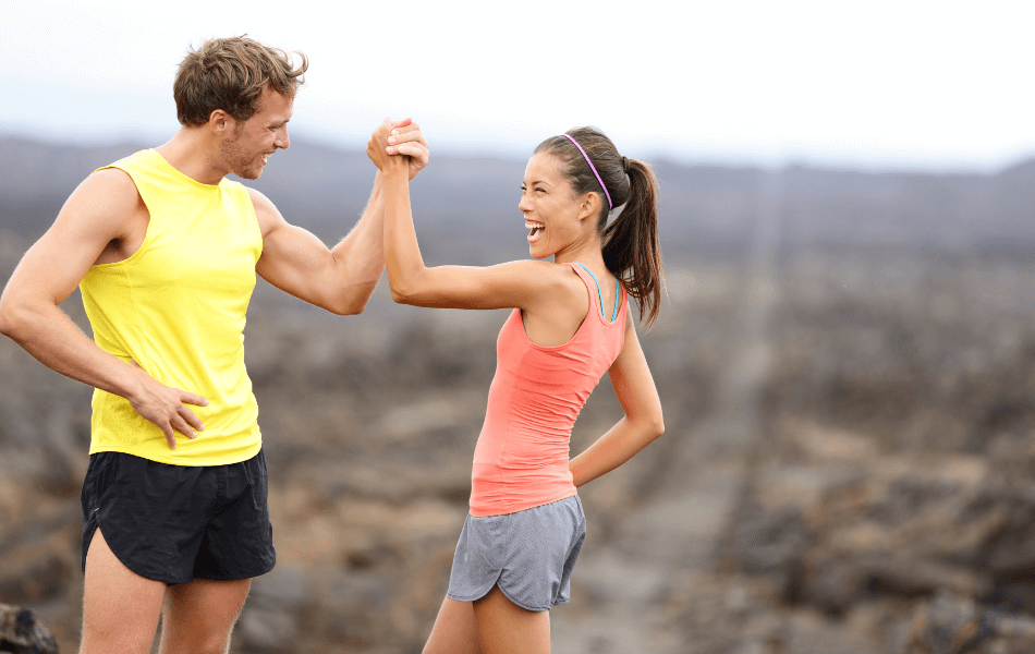 Two people outside in fitness attire giving each other a high-five