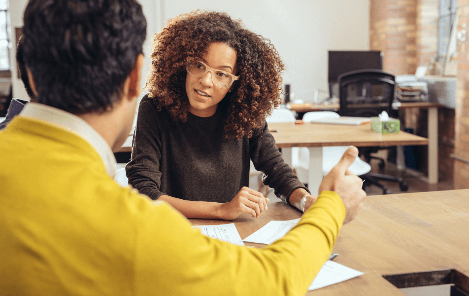 Two people sitting at a table with documents between them