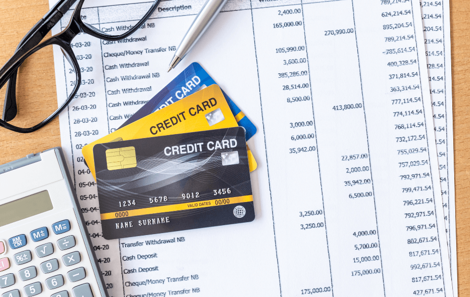 credit card statement with credit cards, a calculator, and glasses on top of it