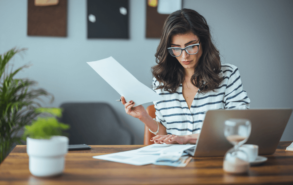 Person on laptop holding documents