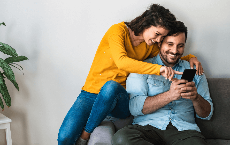 Man and woman looking at a phone on the couch