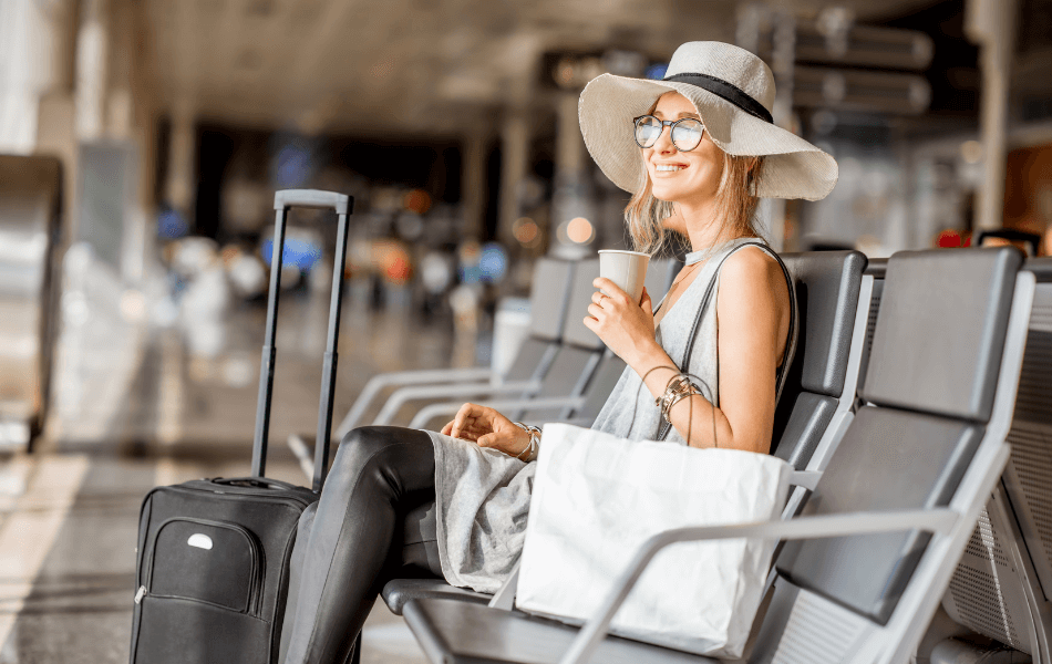Person sitting at airport with luggage and shopping bag