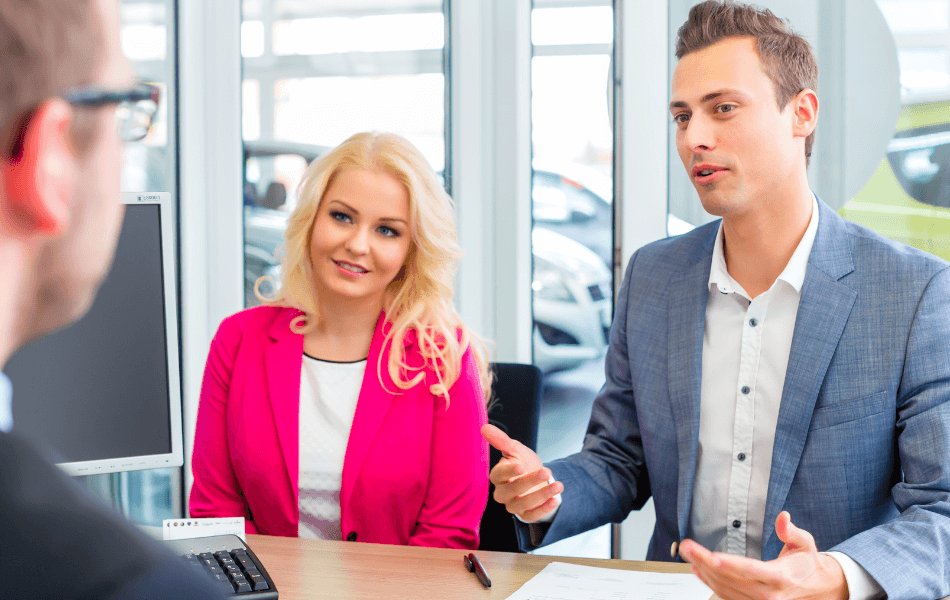 A couple speaking with a car salesman at a dealership