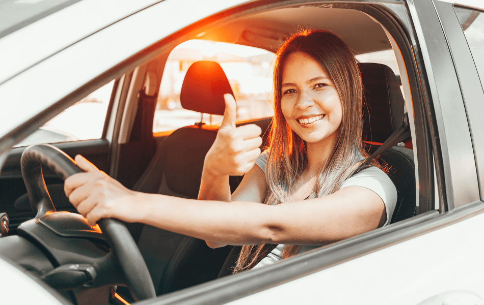 Person giving a thumbs up inside a car
