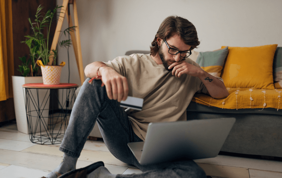 Person holding a credit card and looking at their laptop suspiciously