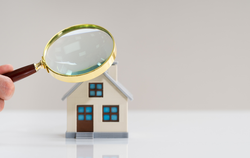 Man holding magnifying glass over small house