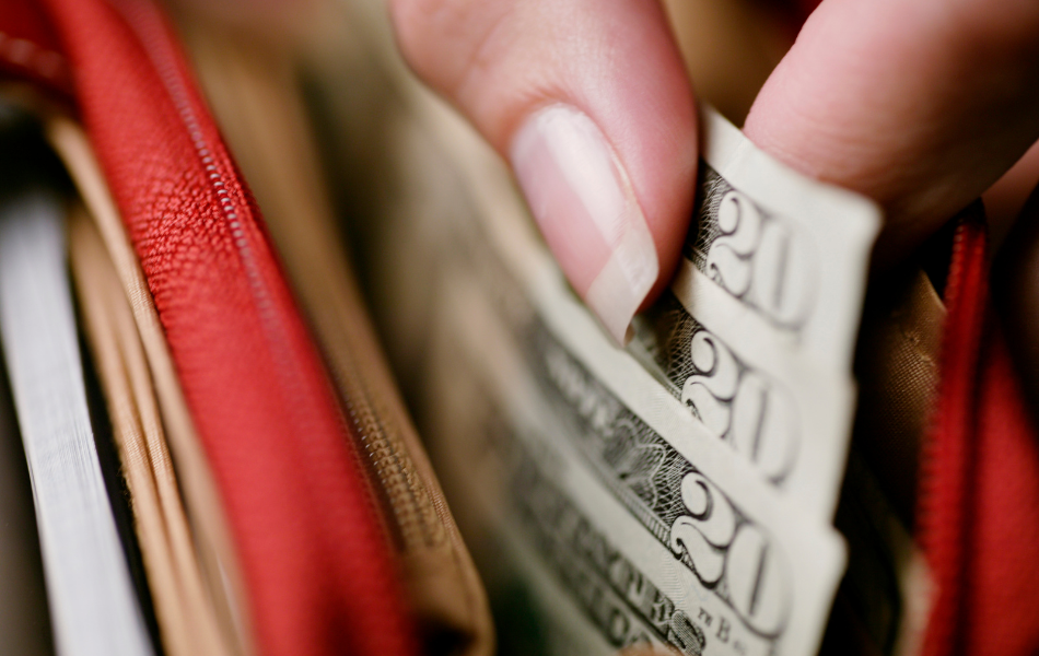 Cut excess spending - woman pulling twenty dollar bills out of her wallet