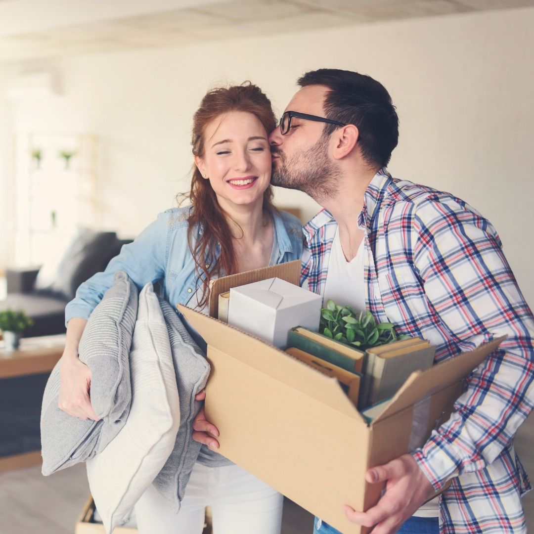 a man kissing woman on cheek holding boxes